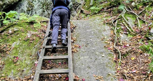 Backpacker comong down a cliff ladder